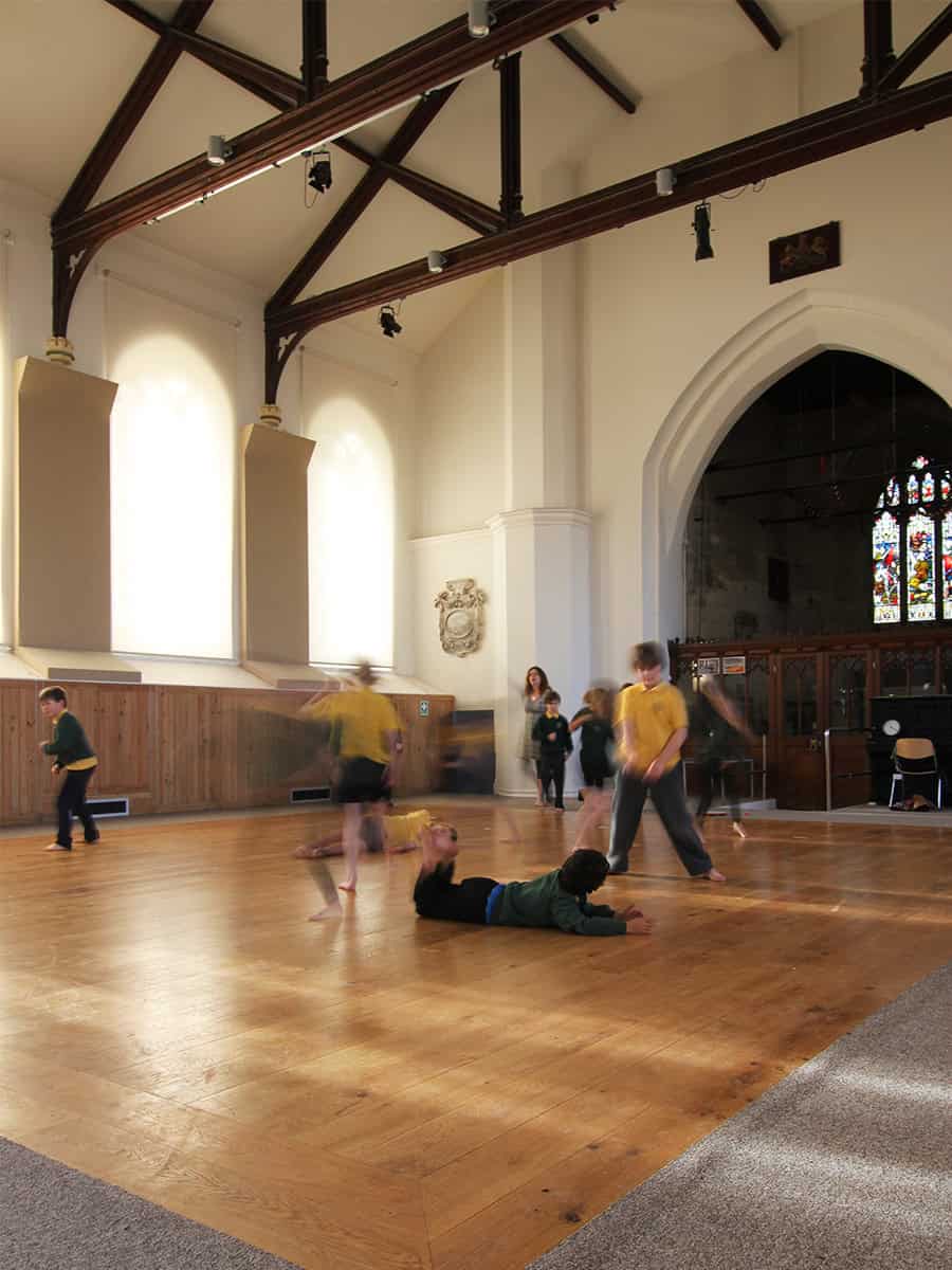 Horsley Church nave with children at play, stained glass window and timber roof trusses